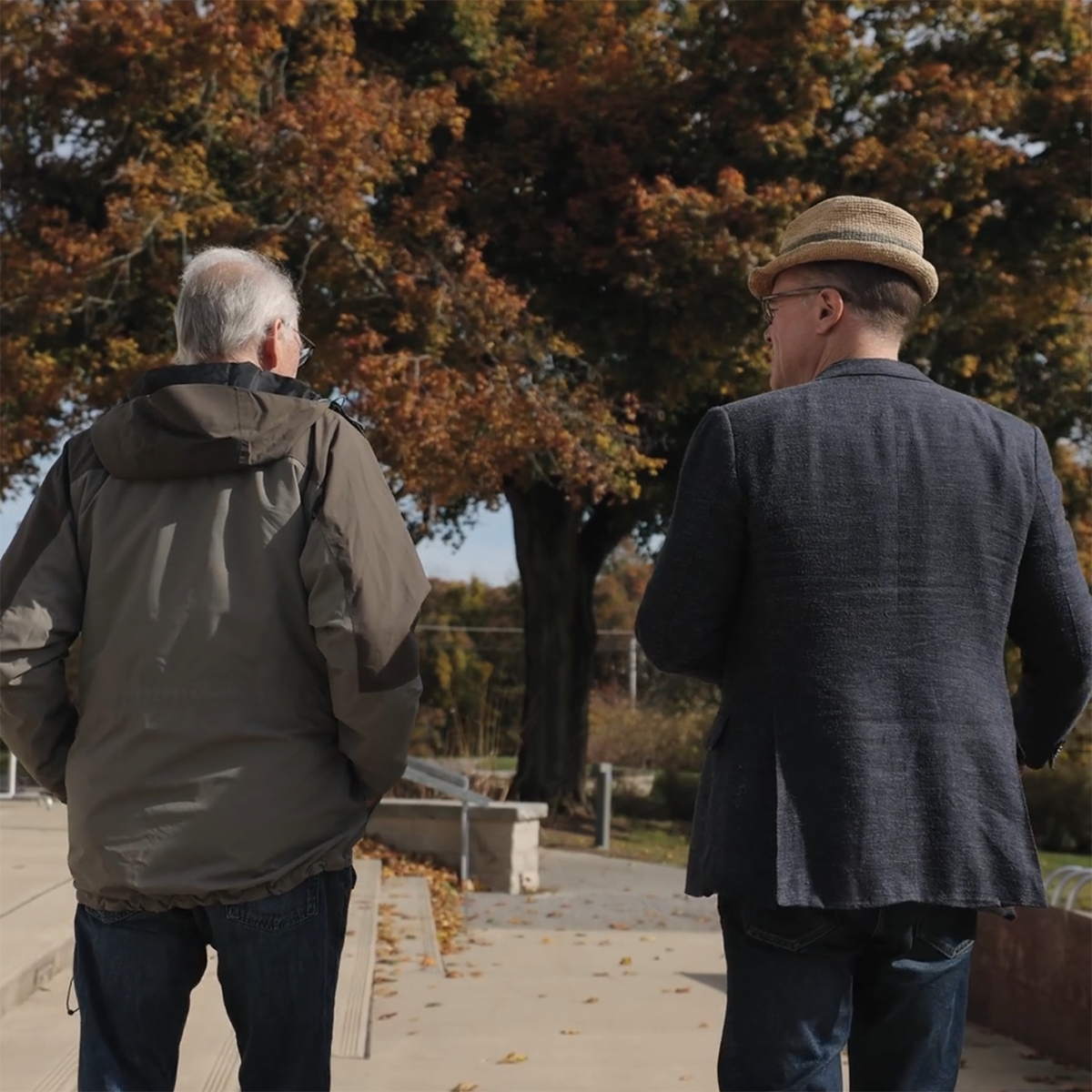 Photo of two men walking away from the camera, conversing together on Eden Hall Campus